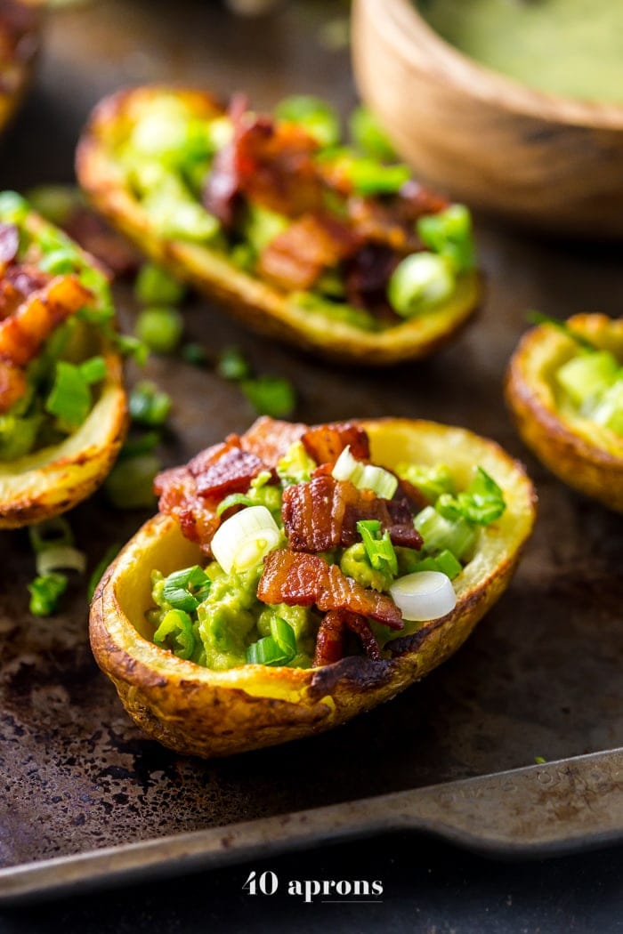 These paleo potato skins are seriously perfect paleo tailgate food. These paleo potato skins are super crispy and easy to make, loaded with a quick guacamole, crispy bacon, green onions, and ranch dressing. Yep, these Whole30 potato skins are perfect alongside buffalo wings and beer, and they'll quickly become your favorite paleo tailgate food. 