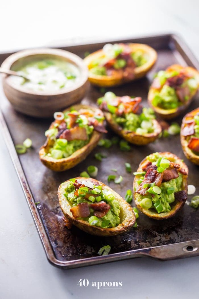 These paleo potato skins are seriously perfect paleo tailgate food. These paleo potato skins are super crispy and easy to make, loaded with a quick guacamole, crispy bacon, green onions, and ranch dressing. Yep, these Whole30 potato skins are perfect alongside buffalo wings and beer, and they'll quickly become your favorite paleo tailgate food. 