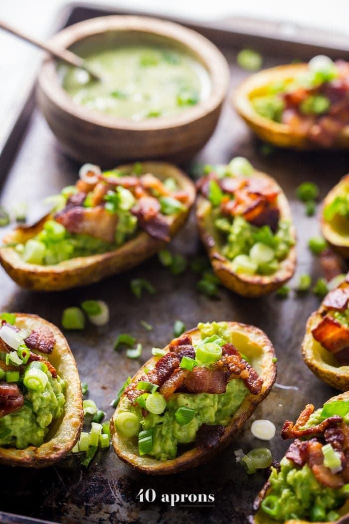 These paleo potato skins are seriously perfect paleo tailgate food. These paleo potato skins are super crispy and easy to make, loaded with a quick guacamole, crispy bacon, green onions, and ranch dressing. Yep, these Whole30 potato skins are perfect alongside buffalo wings and beer, and they'll quickly become your favorite paleo tailgate food. 