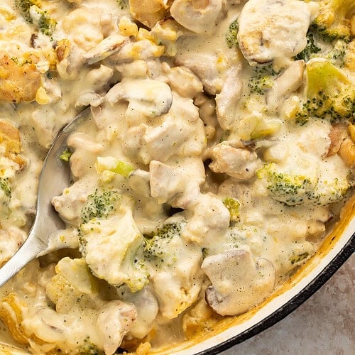 Whole30 chicken and broccoli casserole in cast iron skillet with creamy sauce and spoon