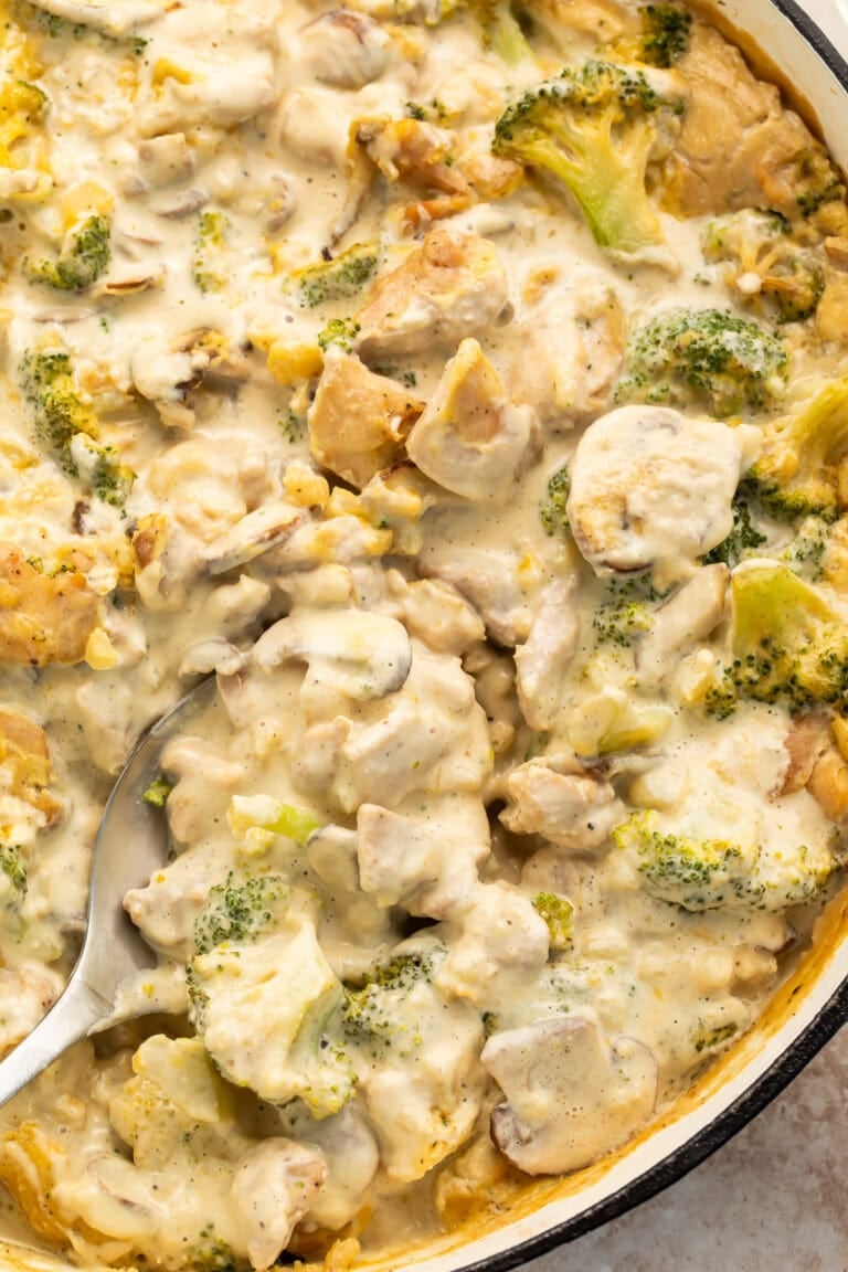 Whole30 chicken and broccoli casserole in cast iron skillet with creamy sauce and spoon