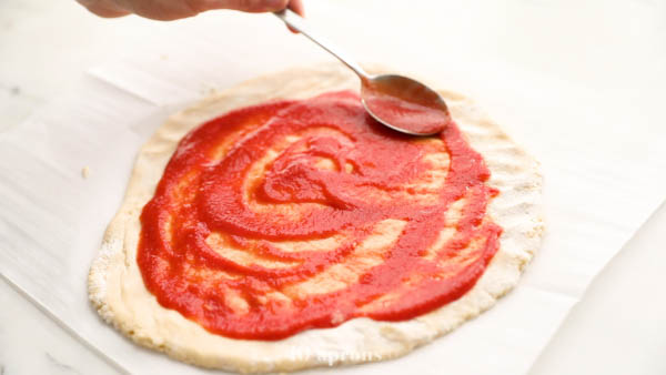 Spread sauce on paleo pizza crust
