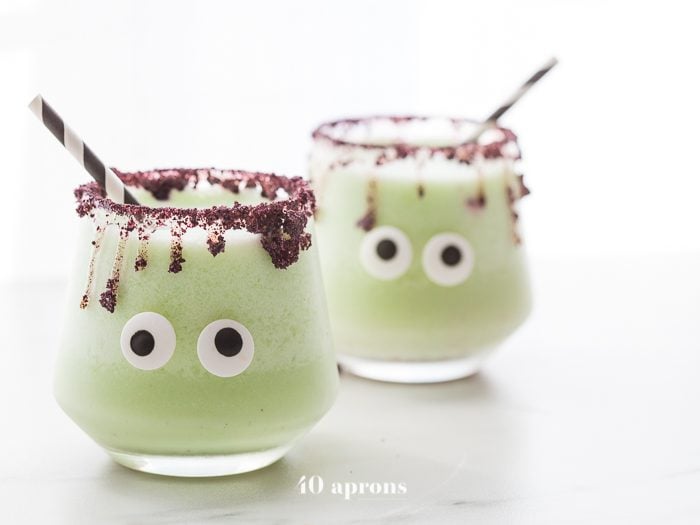 Monsteritas green Halloween cocktails with purple dripping rim and candy monster eyes in glasses with a black and white straw