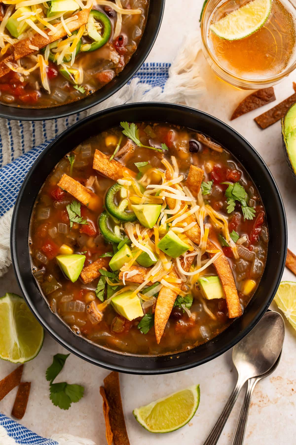 Overhead view of two bowls of turkey tortilla soup with lime beer garnished table setting