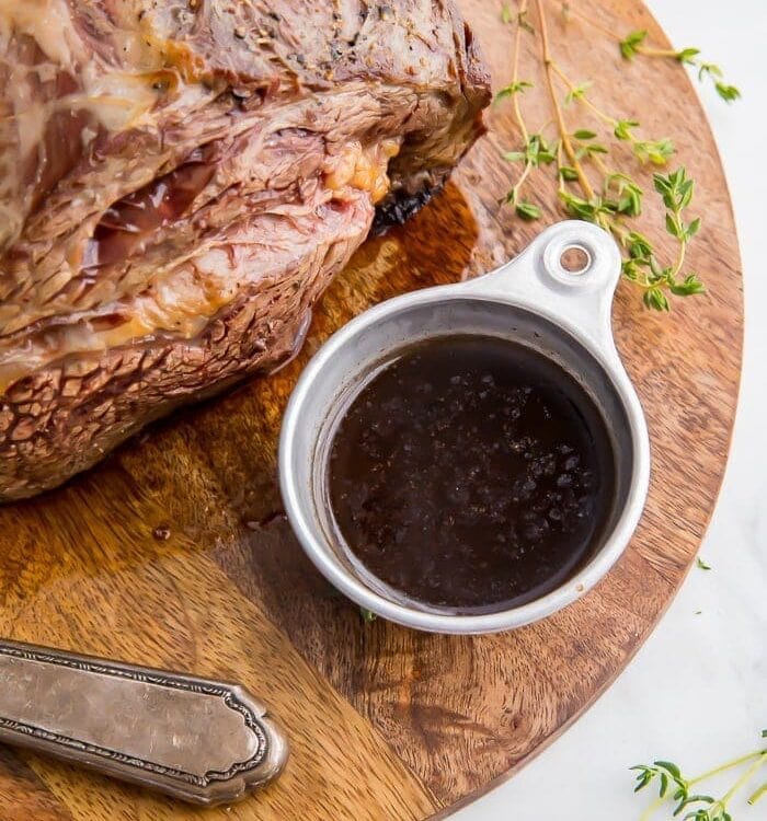 A cup of au jus sauce next to prime rib