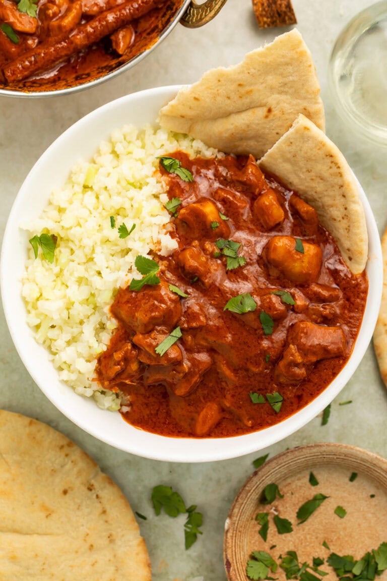 Bowl of butter chicken with cauliflower rice and naan.
