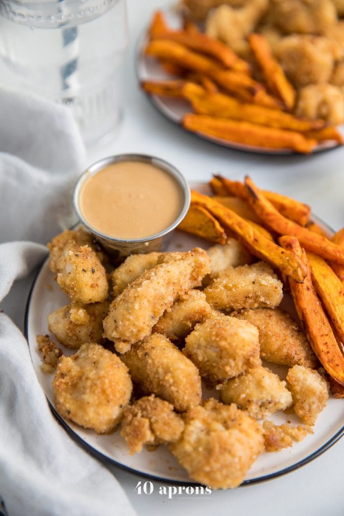 Paleo Whole30 chicken nuggets recipe on a plate with dipping sauce sauce and sweet potato fries