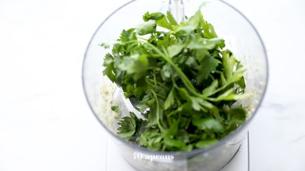 Add fresh herbs to food processor and chop