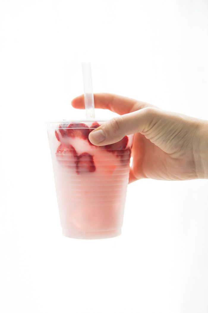 Hand holding healthy pink drink strawberry refresher