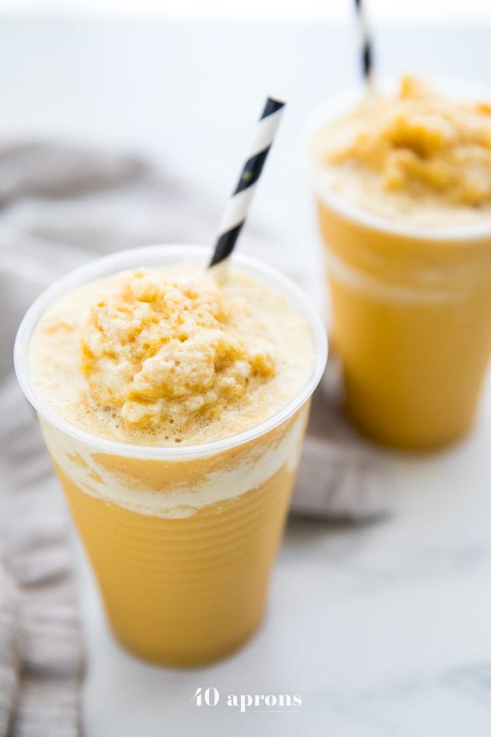 Two frozen golden milk turmeric frappuccinos in to-go cups with black and white straws