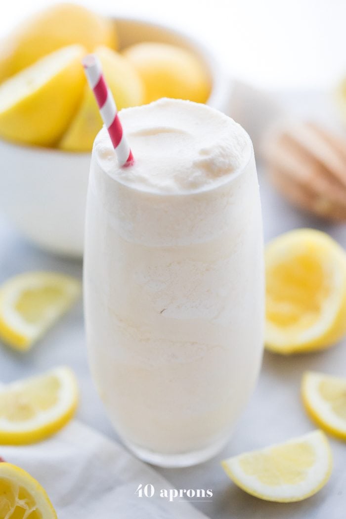 Healthy Chick Fil A frosted lemonade in a glass with a straw and lemons in the background