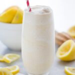 Healthy frosted lemonade in a glass with a straw and lemons in the background