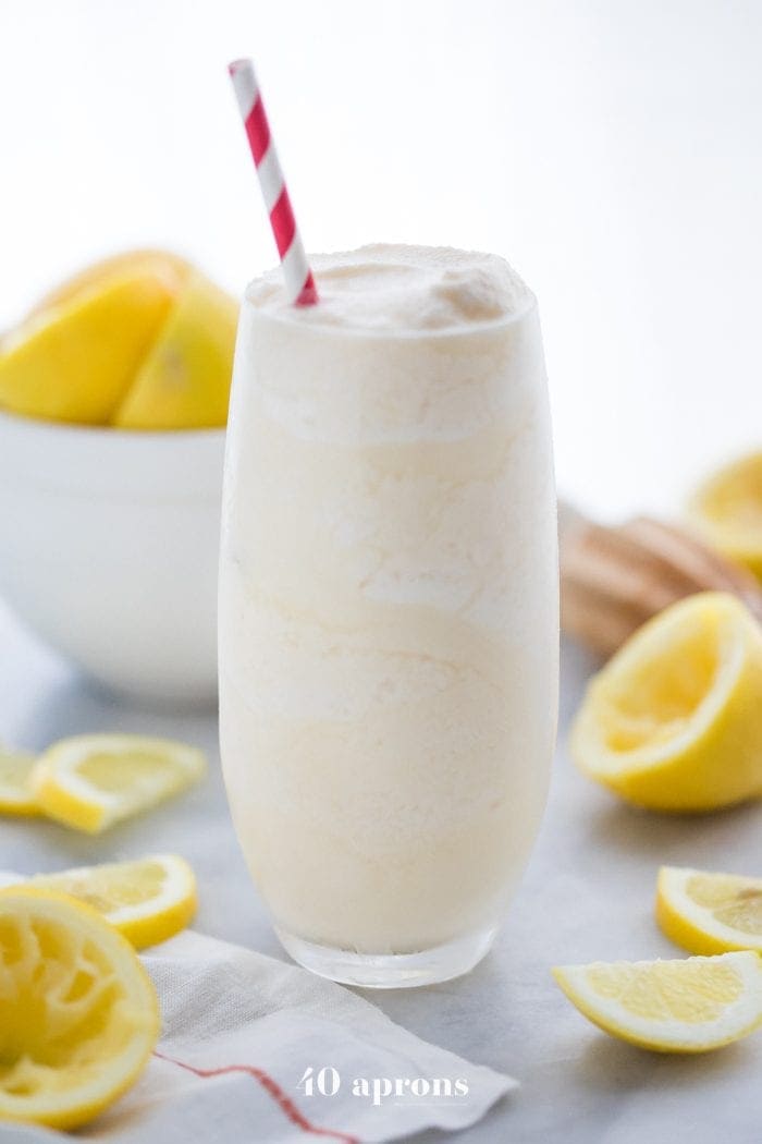 Healthy Chick Fil A frosted lemonade in a glass with a straw and lemons in the background