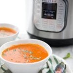 Perfect Whole30 Instant Pot tomato soup (vegan) in two bowls in front of the Instant Pot