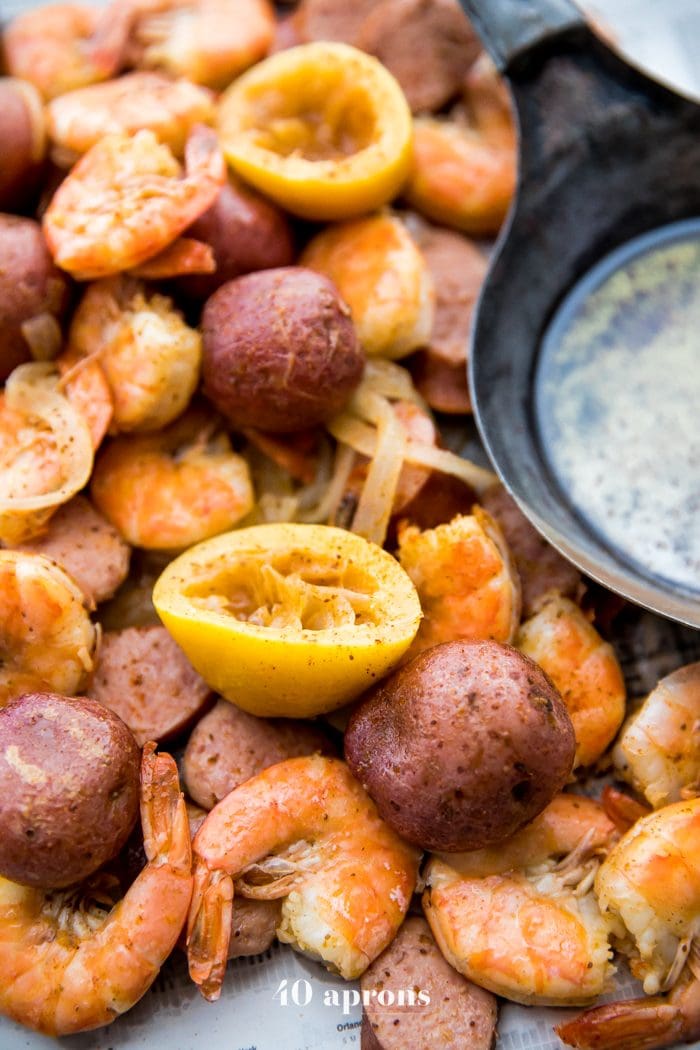 Whole30 shrimp boil with sausage, potatoes, and garlic ghee on newspaper
