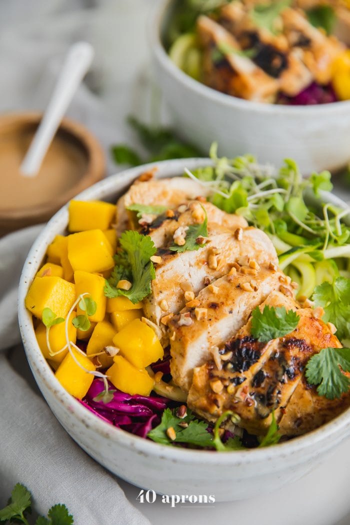 Whole30 Thai chicken zoodle bowls with "peanut sauce" in a bowl with garnishes