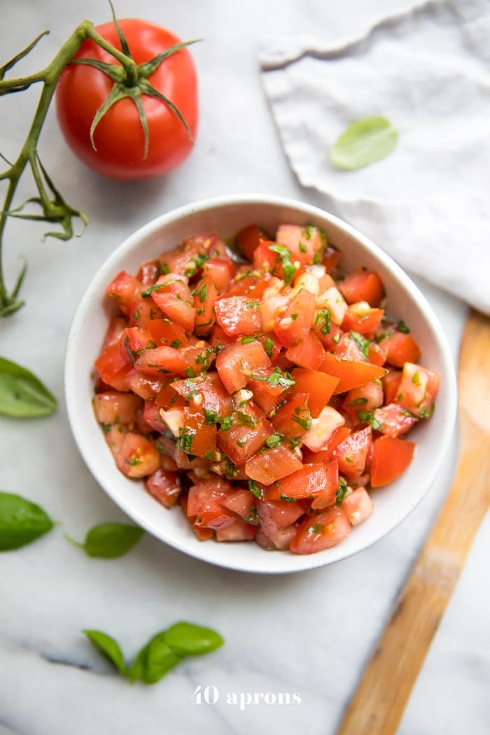 Tazón de bruschetta fresca con tomates, albahaca y ajo, Tomates y albahaca fresca al lado