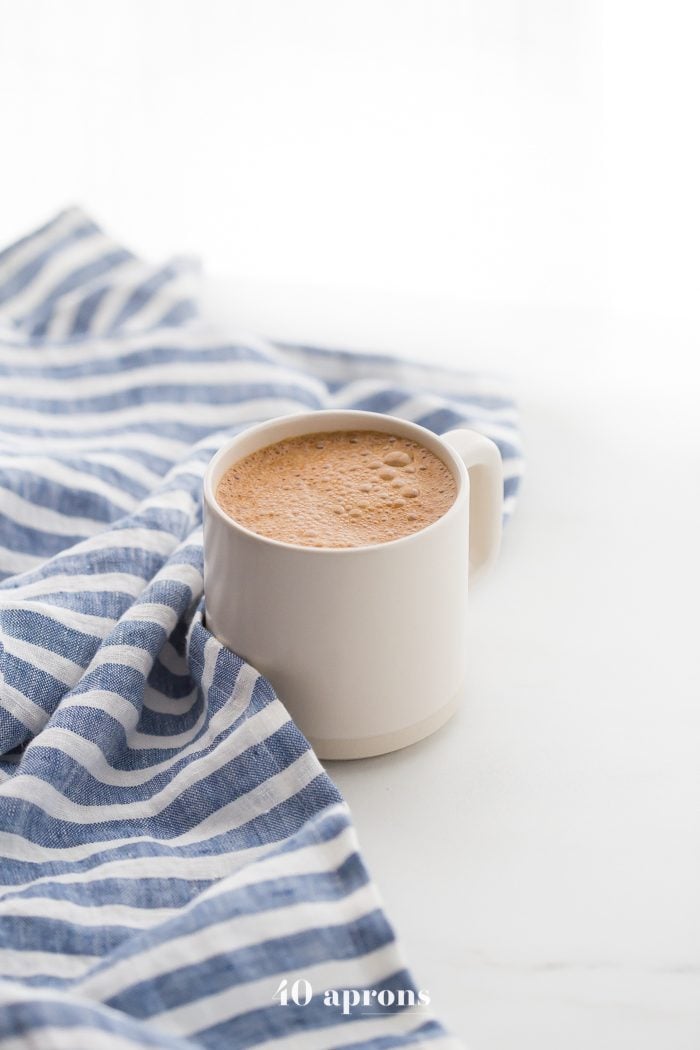 A mug of miracle maca latte with a blue-striped towel
