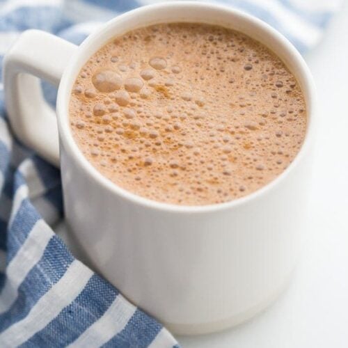 A mug of miracle maca latte with a blue-striped towel