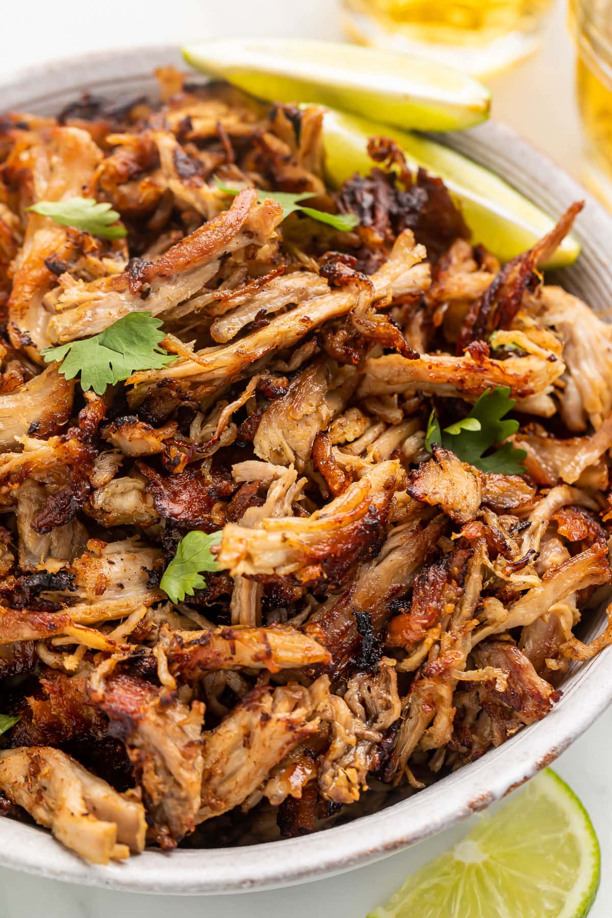 A bowl of slow cooker pork carnitas on a table.