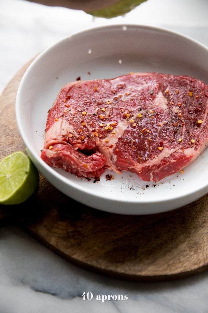 Squeeze lime juice over the steak after it's coated with crushed red pepper, black pepper, and salt