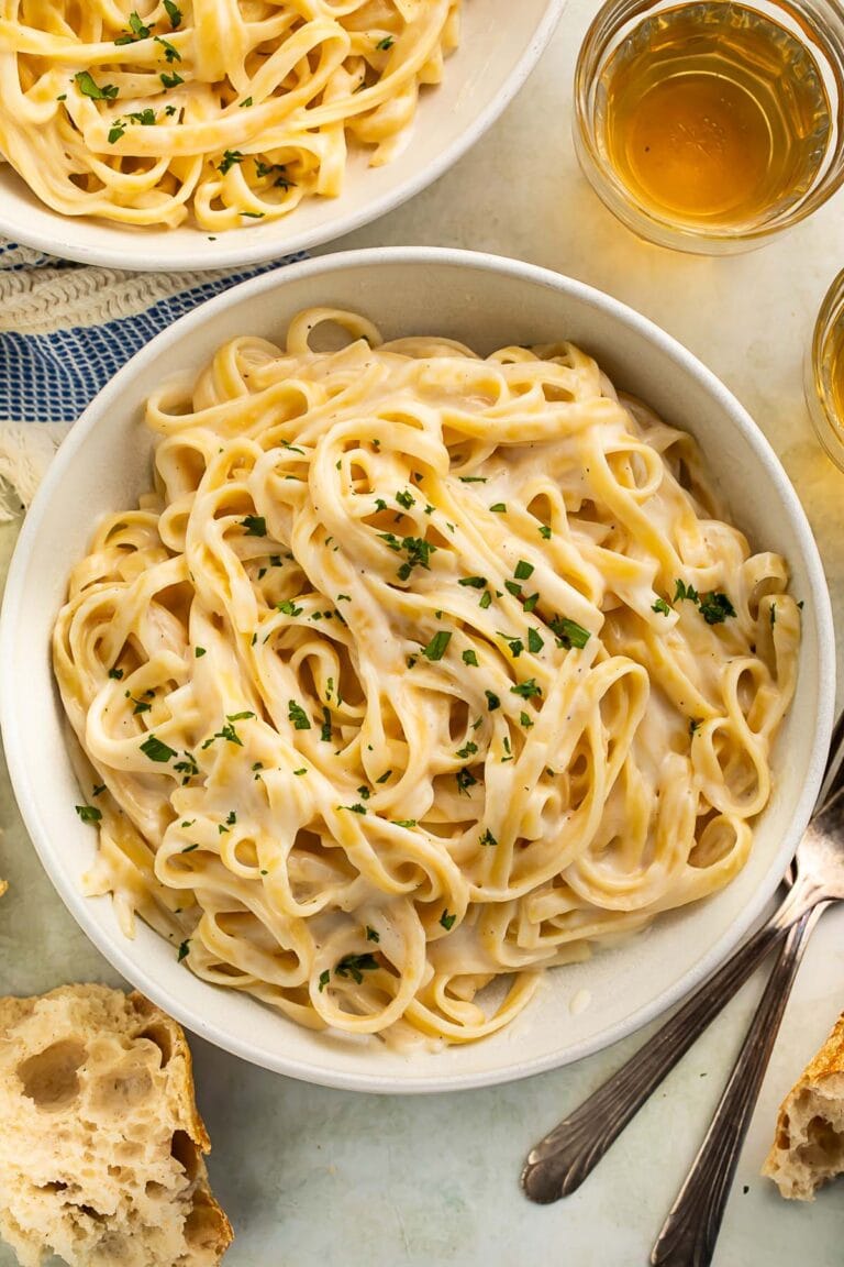 A bowl of creamy cottage cheese alfredo on fettuccine garnished with chopped parsley.