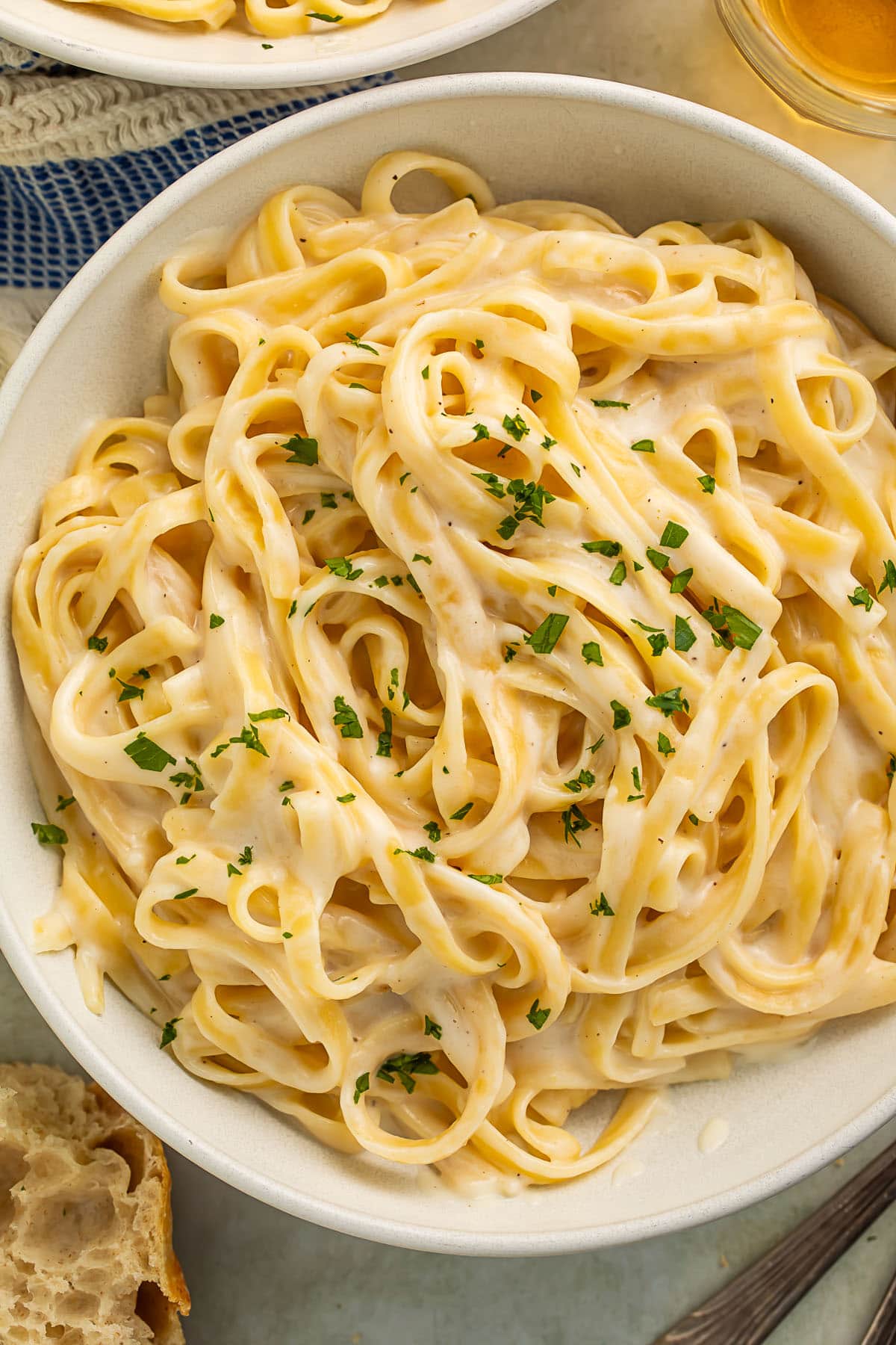 A bowl of creamy cottage cheese alfredo on fettuccine garnished with chopped parsley.