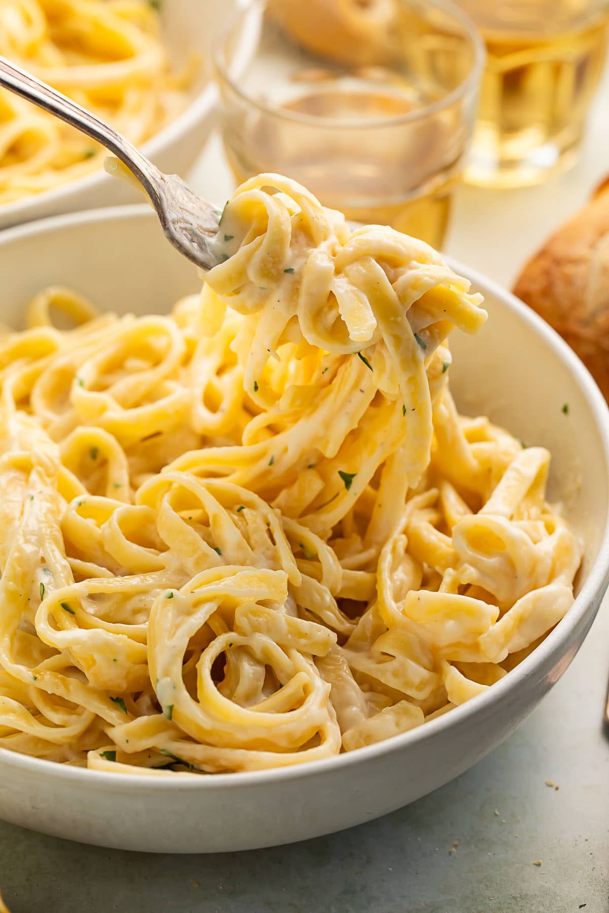 Fettuccine with creamy cottage cheese alfredo wrapped around a fork being lifted out of a large bowl.