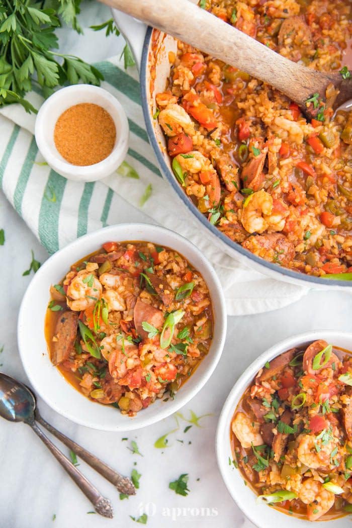 Whole30 healthy jambalaya with cauliflower rice in two bowls and a Dutch oven