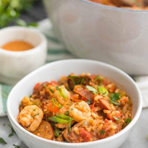 Whole30 healthy jambalaya with cauliflower rice in two bowls and a Dutch oven