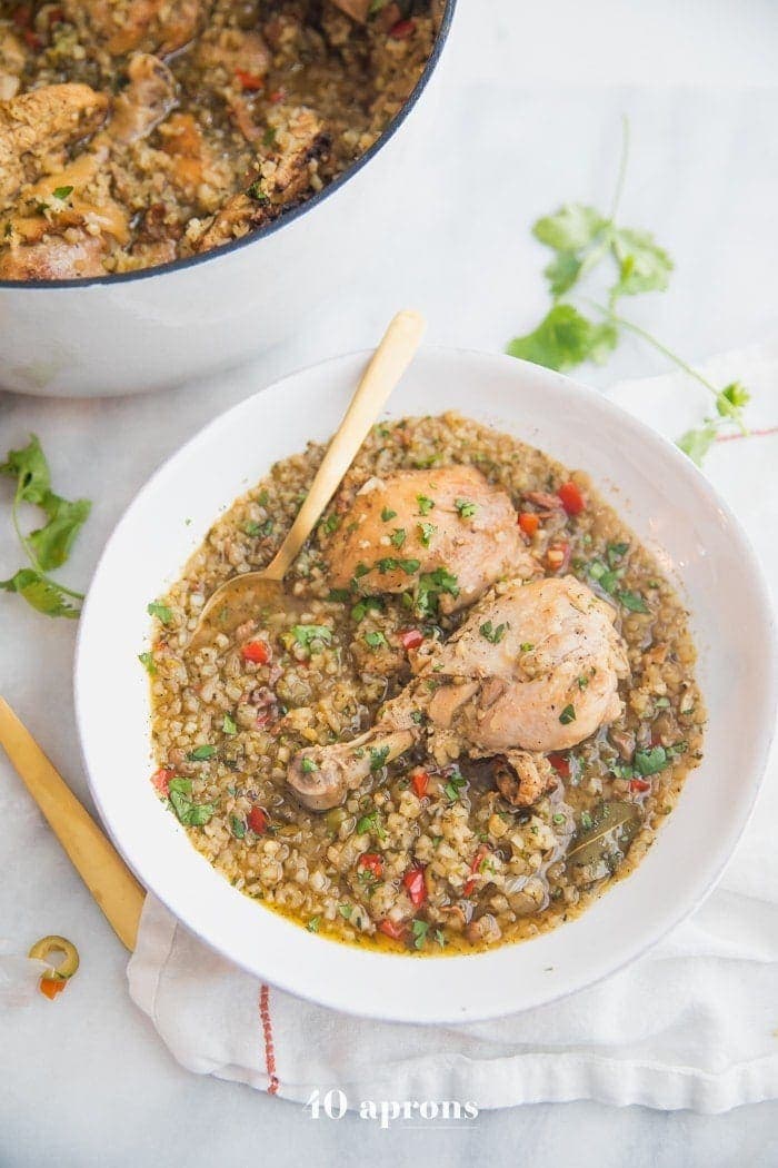 Healthy Spanish chicken and rice stew in a bowl with a pot of the stew next to it