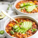 Two bowls of Instant Pot Whole30 chili with butternut squash topped with jalapenos and avocados with Instant Pot in background