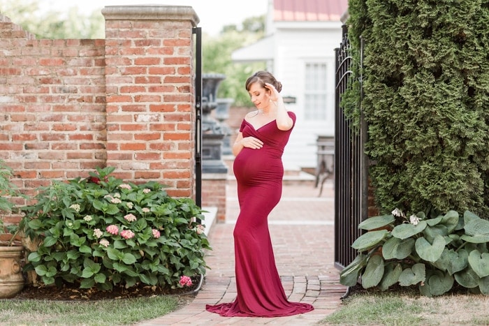 Pregnant woman in long burgundy dress outside