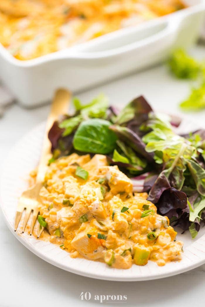 Paleo buffalo chicken casserole on a plate with salad and baking dish in the back
