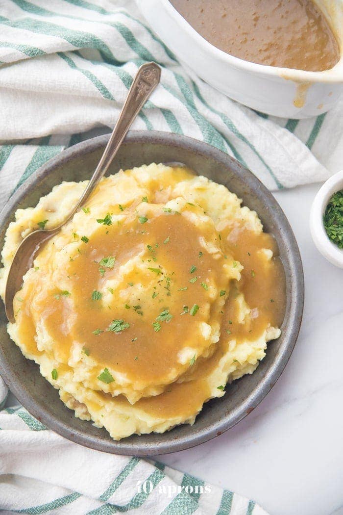 bowl of creamy mashed potatoes topped with a rich Paleo Gravy ans some chopped chives