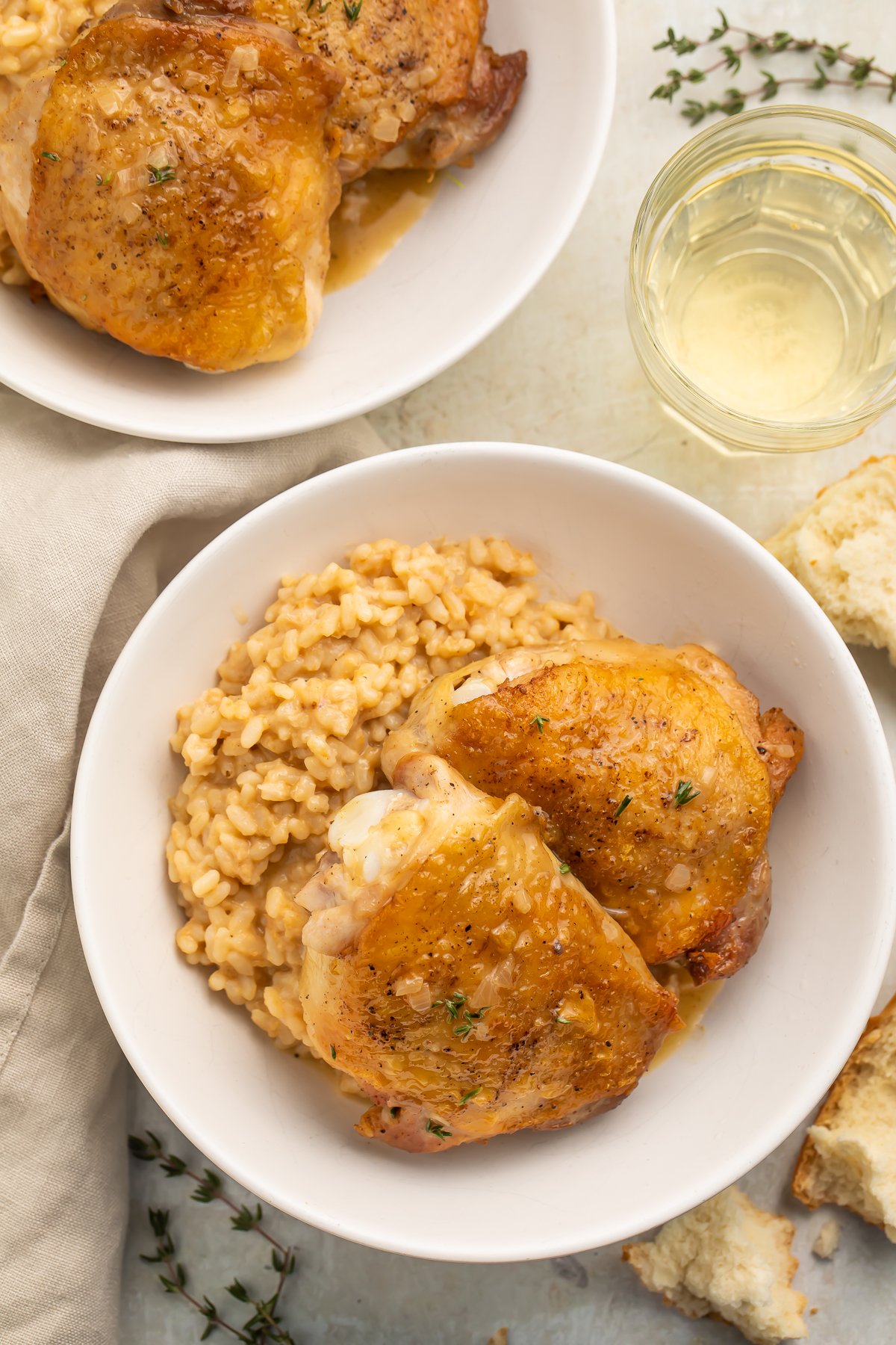 Pan-seared chicken thighs in pan sauce plated with rice in a large white bowl.