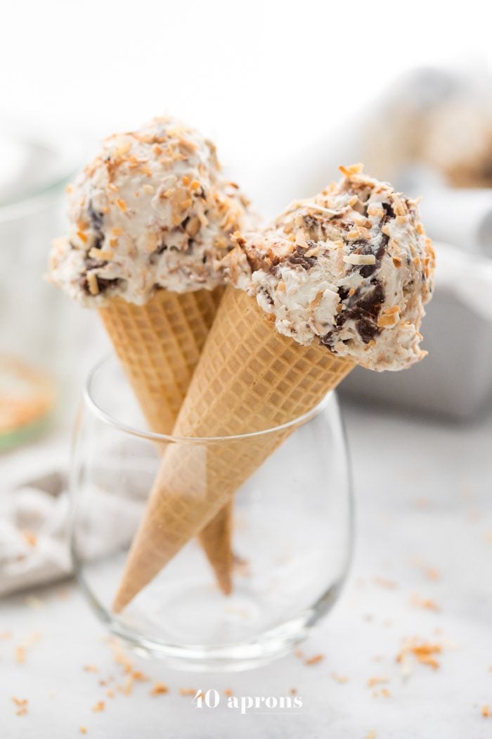 Samoas cookies ice cream in two cones in a glass with ice cream container in the background