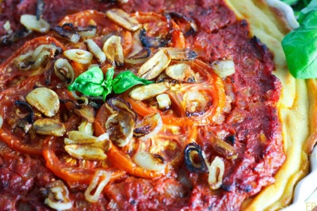 Close-up of Whole30 Tomato Tart decorated with fried garlic and fresh basil leaves