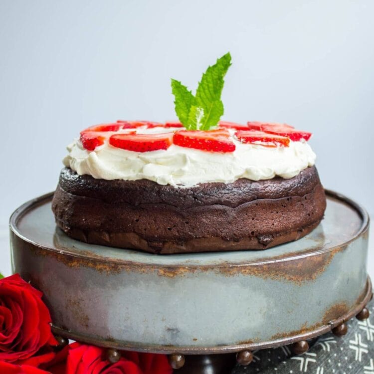 Keto Flourless Chocolate Dessert Torte topped with whipped cream on a cake stand