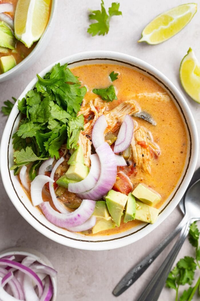 overhead image of whole30 instant pot chicken tortilla-less soup in a bowl with fresh cilantro, avocado, and red onion on top