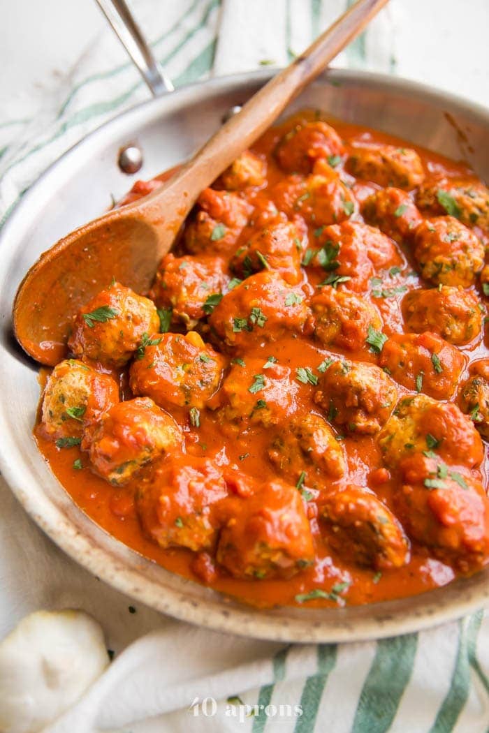 Italian meatballs in creamy tomato sauce in a skillet on a dish towel