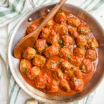 Italian Whole30 meatballs in creamy tomato sauce in a skillet on a dish towel