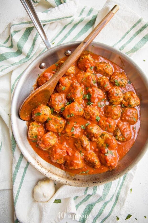 Italian Whole30 meatballs in creamy tomato sauce in a skillet on a dish towel