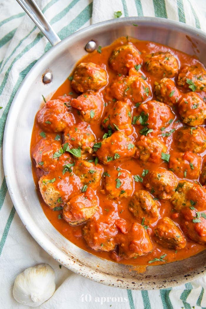 Italian Whole30 meatballs in creamy tomato sauce in a skillet on a dish towel