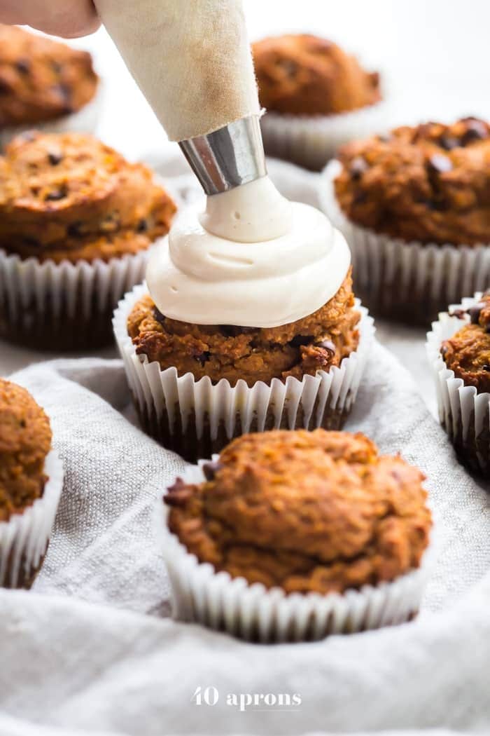 pumpkin muffins being iced with cream cheese frosting