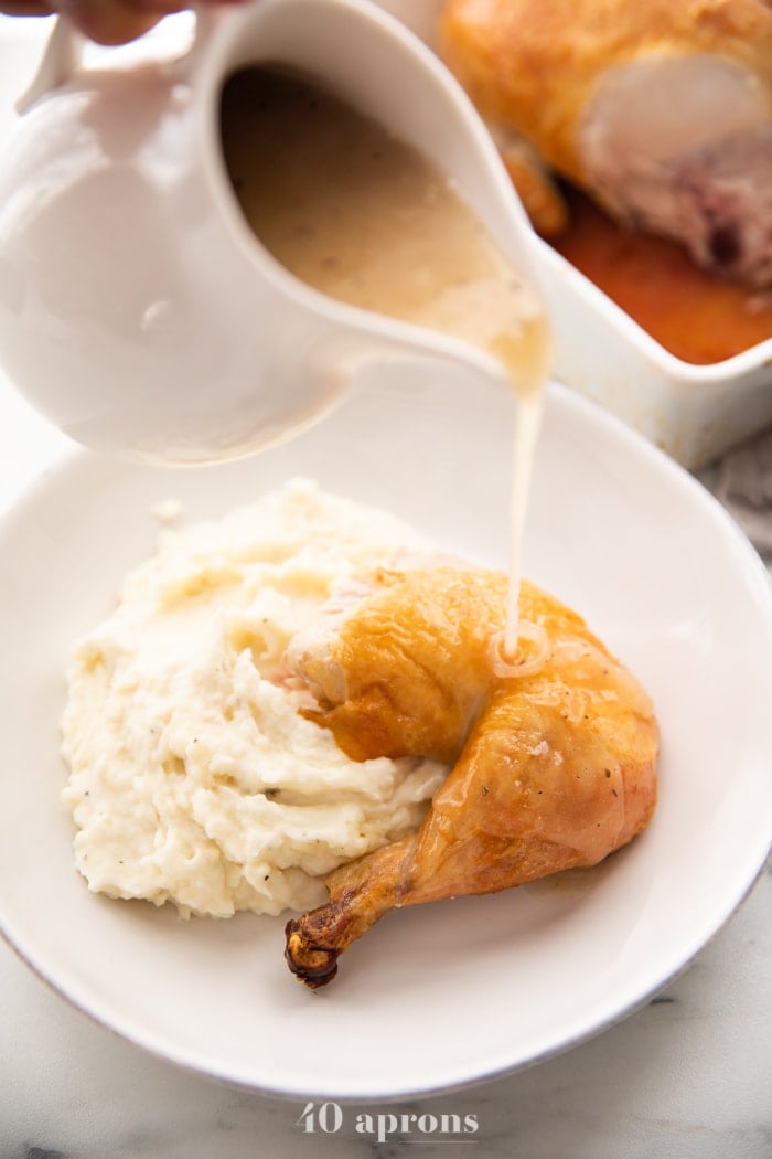 Best easy roast chicken cut into leg and thigh over mashed potatoes with gravy pouring over