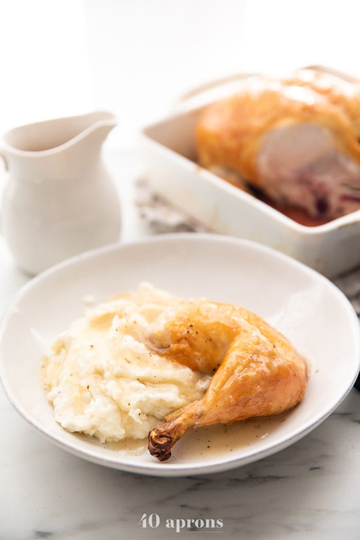 Best easy roast chicken cut into leg and thigh over mashed potatoes with gravy pouring over