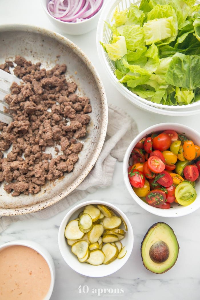 Loaded Whole30 burger bowls ingredients, like ground beef, romaine, tomatoes, avocado, pickles, special sauce
