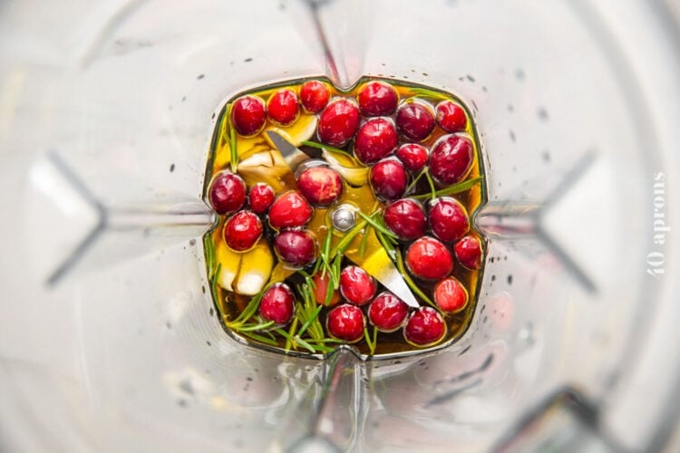 Ingredients for a cranberry olive oil marinade with fresh rosemary in a large standard blender.