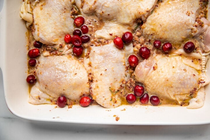 Chicken thighs and cranberry marinade in a large baking dish.